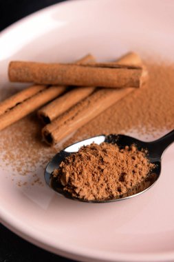 Tarçın tozu ve plaka üzerinde sopa ile Kaşık, closeup