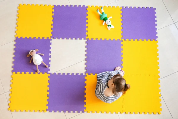 Mała dziewczynka z zaburzeniami autystycznych siedzi na podłodze, widok z góry — Zdjęcie stockowe