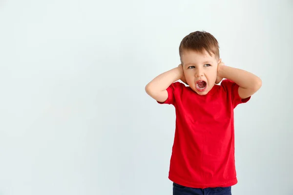 Screaming little boy with autistic disorder covering ears on light background — Stock Photo, Image