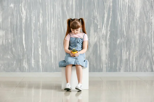 Trauriges kleines Mädchen mit autistischer Störung hält Pflanze im Haus — Stockfoto