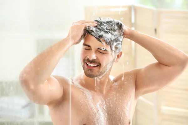 Handsome man washing hair at home