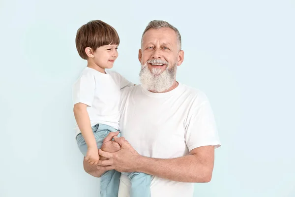 Cute little boy with grandfather on light background — Stock Photo, Image