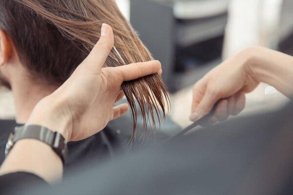 Female hairdresser working with client in salon, closeup