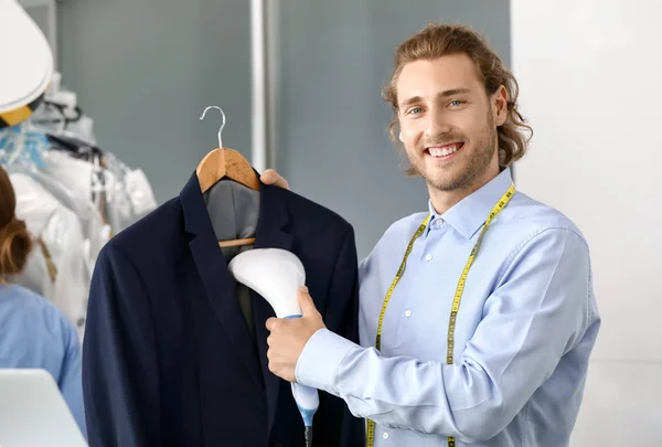 Worker of modern dry-cleaner\'s steaming clothes