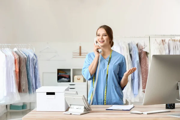 Worker of modern dry-cleaner's talking by phone at reception — Stock Photo, Image