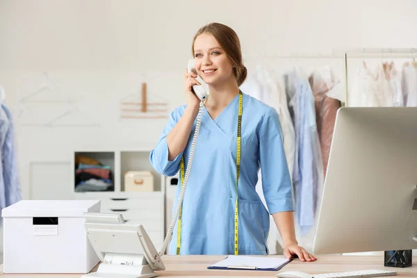 Worker of modern dry-cleaner\'s talking by phone at reception