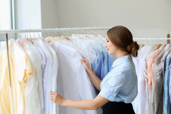 Worker of modern dry-cleaner's near rack with clothes — Stock Photo, Image