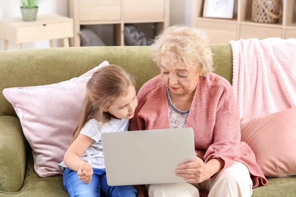 Χαριτωμένο μικρό κορίτσι με τη γιαγιά χρησιμοποιώντας το laptop στο σπίτι — Φωτογραφία Αρχείου