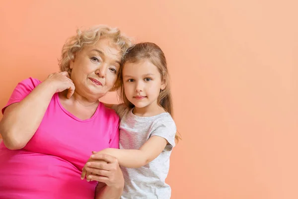 Χαριτωμένο μικρό κορίτσι με τη γιαγιά στο φόντο χρώμα — Φωτογραφία Αρχείου