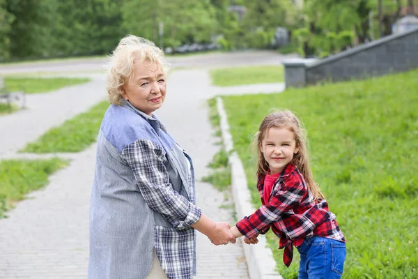 Милая маленькая девочка с бабушкой, гуляющей в парке — стоковое фото