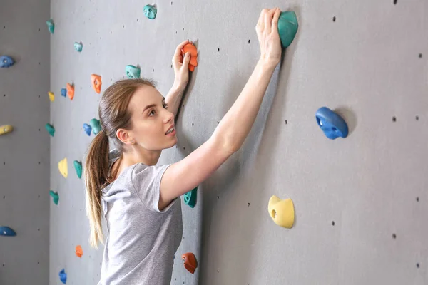 Jovem mulher escalada parede no ginásio — Fotografia de Stock
