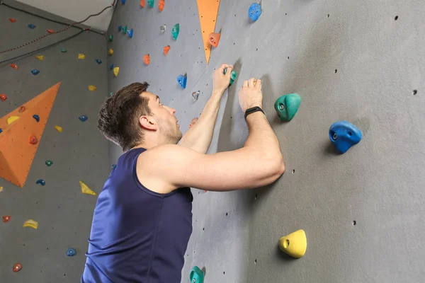 Young man climbing wall in gym — Stock Photo, Image