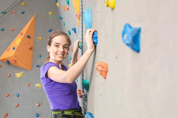 Jovem mulher escalada parede no ginásio — Fotografia de Stock