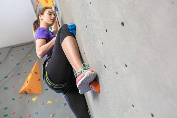 Jovem mulher escalada parede no ginásio — Fotografia de Stock