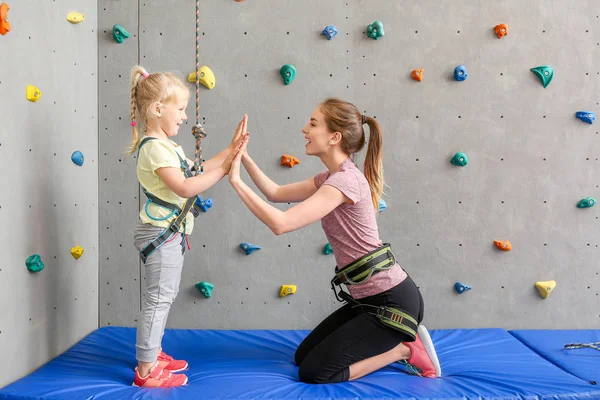 Mała dziewczynka i instruktor dając sobie nawzajem wysoki-pięć w siłowni wspinaczkowej — Zdjęcie stockowe