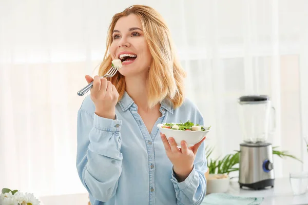 Mulher comendo salada de legumes saudável na cozinha — Fotografia de Stock