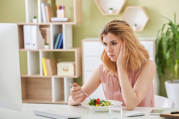 Mulher relutante com salada de legumes saudável no escritório — Fotografia de Stock
