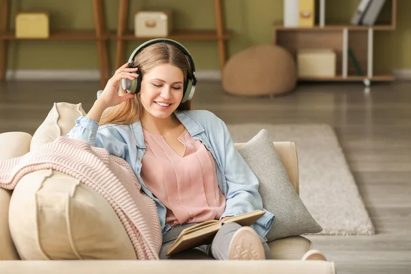 Mladá žena naslouchající hudbě a čtení knih doma — Stock fotografie
