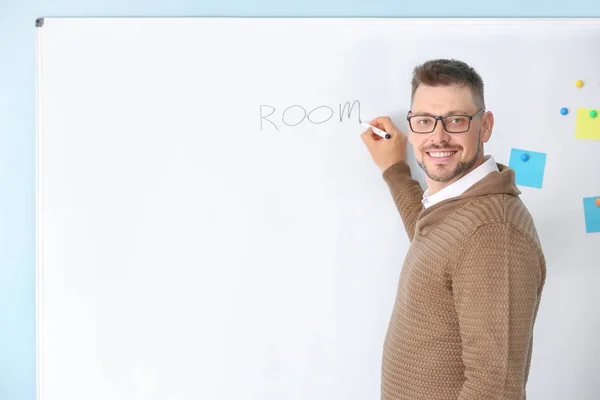 Handsome male teacher writing on blackboard in classroom — Stock Photo, Image