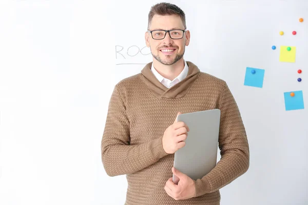 Handsome male teacher with laptop near blackboard in classroom — Stock Photo, Image