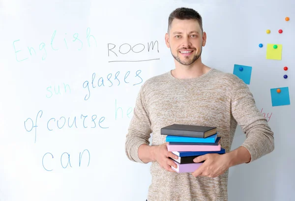 Guru tampan laki-laki dengan buku-buku dekat papan tulis di kelas — Stok Foto