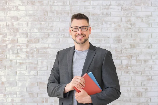 Handsome male teacher against brick wall — Stock Photo, Image