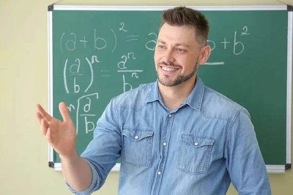 Profesor de matemáticas guapo cerca de pizarra en el aula — Foto de Stock