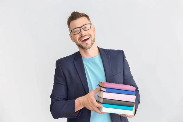 Przystojny mężczyzna nauczyciel z książek na jasnym tle — Zdjęcie stockowe