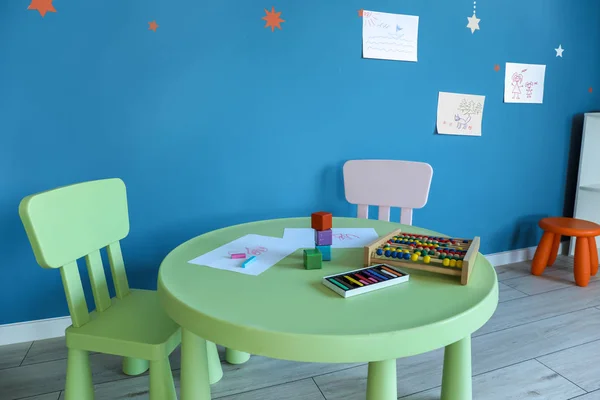 Table with abacus and kid's drawing in kindergarten — Stock Photo, Image