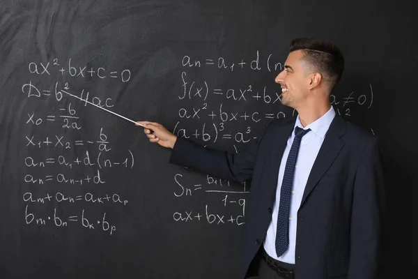 Profesor de matemáticas guapo cerca de pizarra en el aula — Foto de Stock