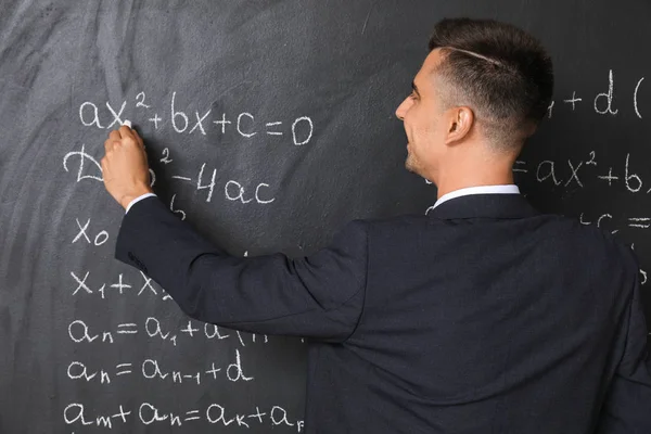 Όμορφος δάσκαλος μαθηματικών που γράφει στον μαυροπίνακα στην τάξη — Φωτογραφία Αρχείου