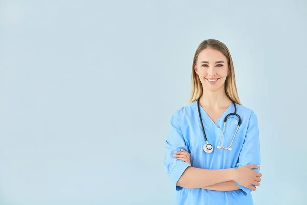 Female nurse with stethoscope on color background — Stock Photo, Image