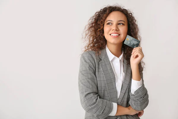 Joven mujer de negocios afroamericana con tarjeta de crédito sobre fondo claro —  Fotos de Stock