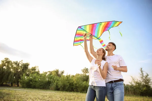 Young couple flying kite outdoors — Stock Photo, Image