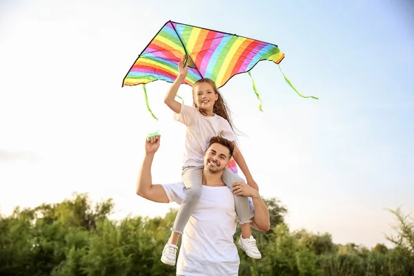 Young man with little daughter flying kite outdoors — Stock Photo, Image