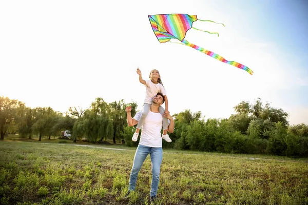 Young man with little daughter flying kite outdoors — Stock Photo, Image