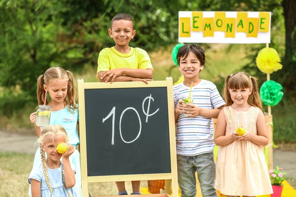 귀여운 어린이들이 공원에서 레모네이드를 파는 모습 — 스톡 사진