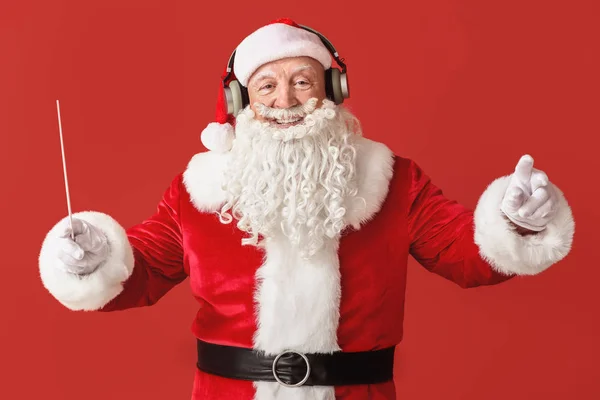 Porträt des Weihnachtsmannes mit Zauberstab, der Musik auf farbigem Hintergrund hört — Stockfoto