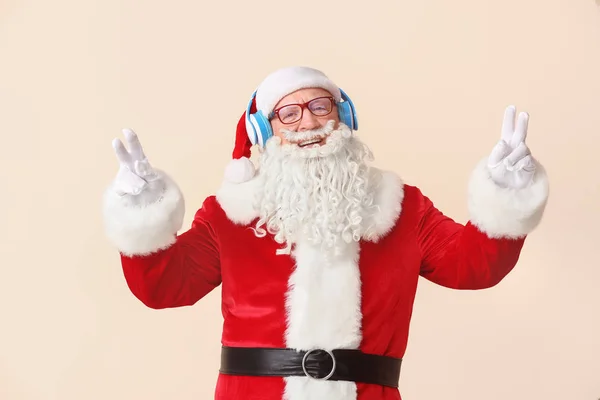 Portrait of Santa Claus listening to music on light background — Stock Photo, Image