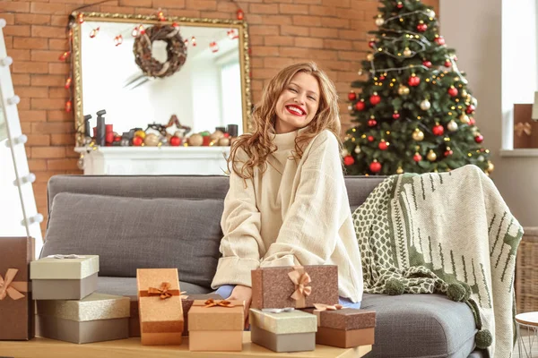 Szczęśliwa młoda kobieta z prezentów świątecznych w domu — Zdjęcie stockowe