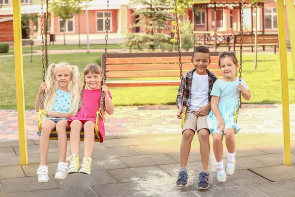 Милые маленькие дети на качелях в парке — стоковое фото