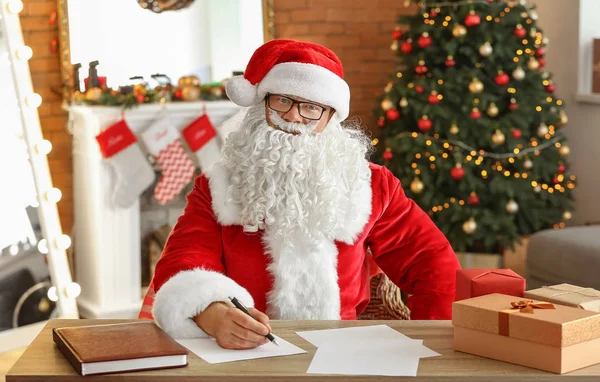 Weihnachtsmann bastelt Geschenkliste im weihnachtlich dekorierten Zimmer — Stockfoto