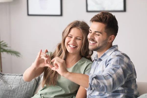 Portrait of happy loving couple holding hands in shape of heart at home — Stock Photo, Image