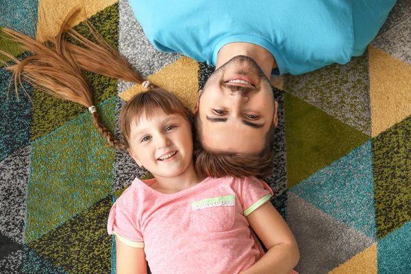 Portrait of happy father with daughter lying on carpet at home — Stock Photo, Image
