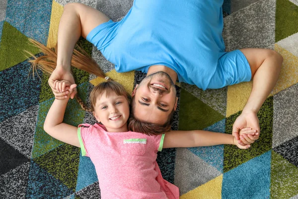 Portrét šťastného otce s dcerou ležící doma na koberci — Stock fotografie