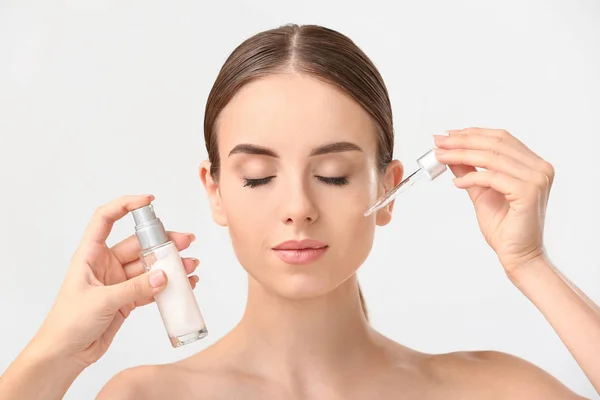 Woman applying serum onto her face against white background — Stock Photo, Image