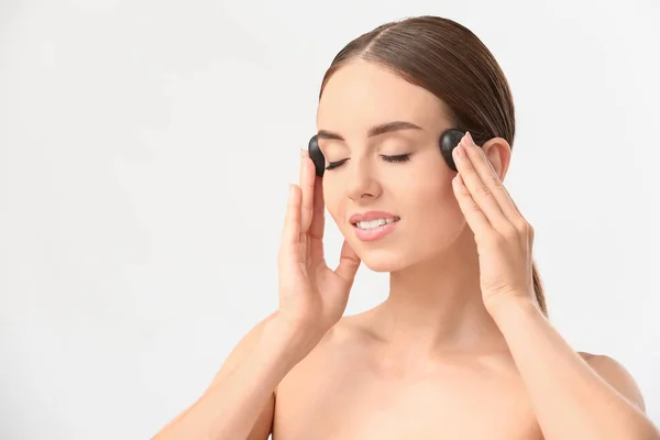 Hermosa mujer masajeando su cara con piedras calientes fondo blanco — Foto de Stock