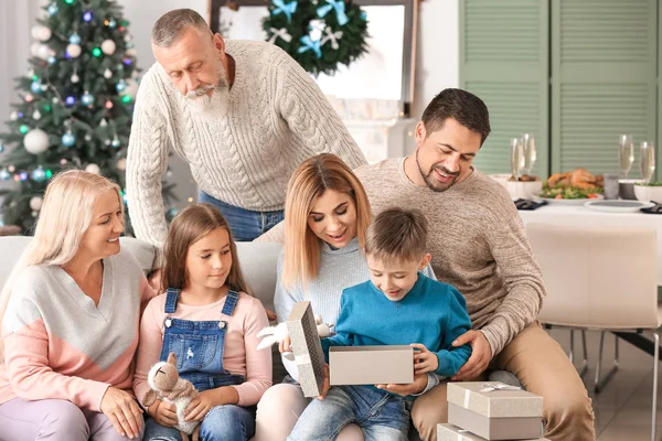 Liten pojke med mottagna julklapp och hans familj hemma — Stockfoto