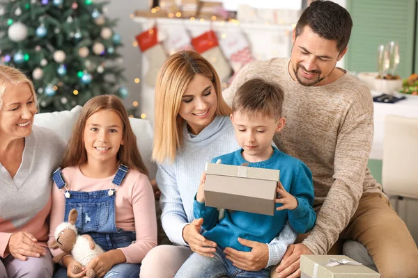 Liten pojke med mottagna julklapp och hans familj hemma — Stockfoto