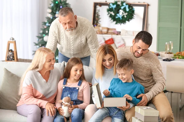 Liten pojke med mottagna julklapp och hans familj hemma — Stockfoto